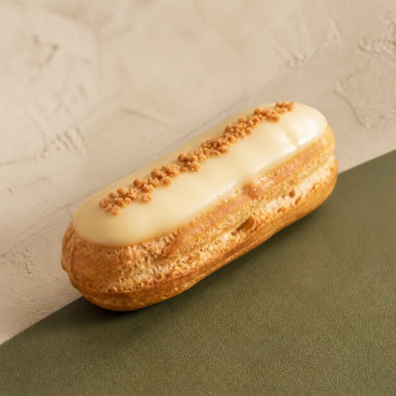 Mini éclair dorado con cobertura clara de vainilla.